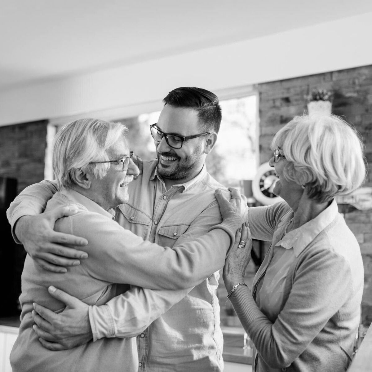 Haszonélvezeti jog alapítása és megszüntetése – családi egyeztetés boldog pillanatban Idős házaspár boldogan öleli fiatal fiát otthoni környezetben, a haszonélvezeti jog alapítása és megszüntetése családi egyeztetésének pillanatát megörökítve.