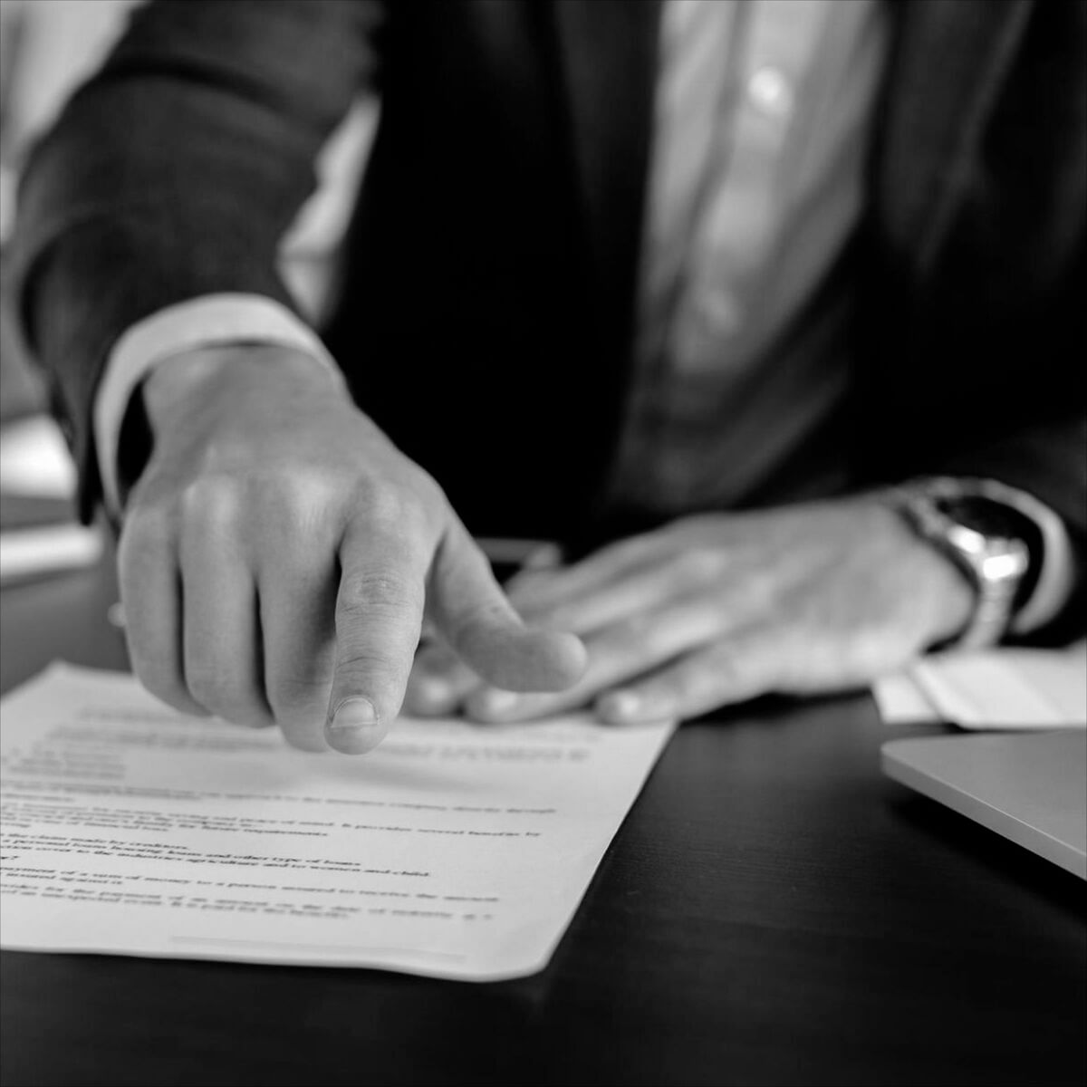 Közös tulajdon megszüntetése szerződés bemutatása ügyvéd által Ügyvéd keze egy asztalon fekvő szerződésre mutat, miközben közös tulajdon megszüntetése témájú dokumentumot magyaráz az ügyfélnek.