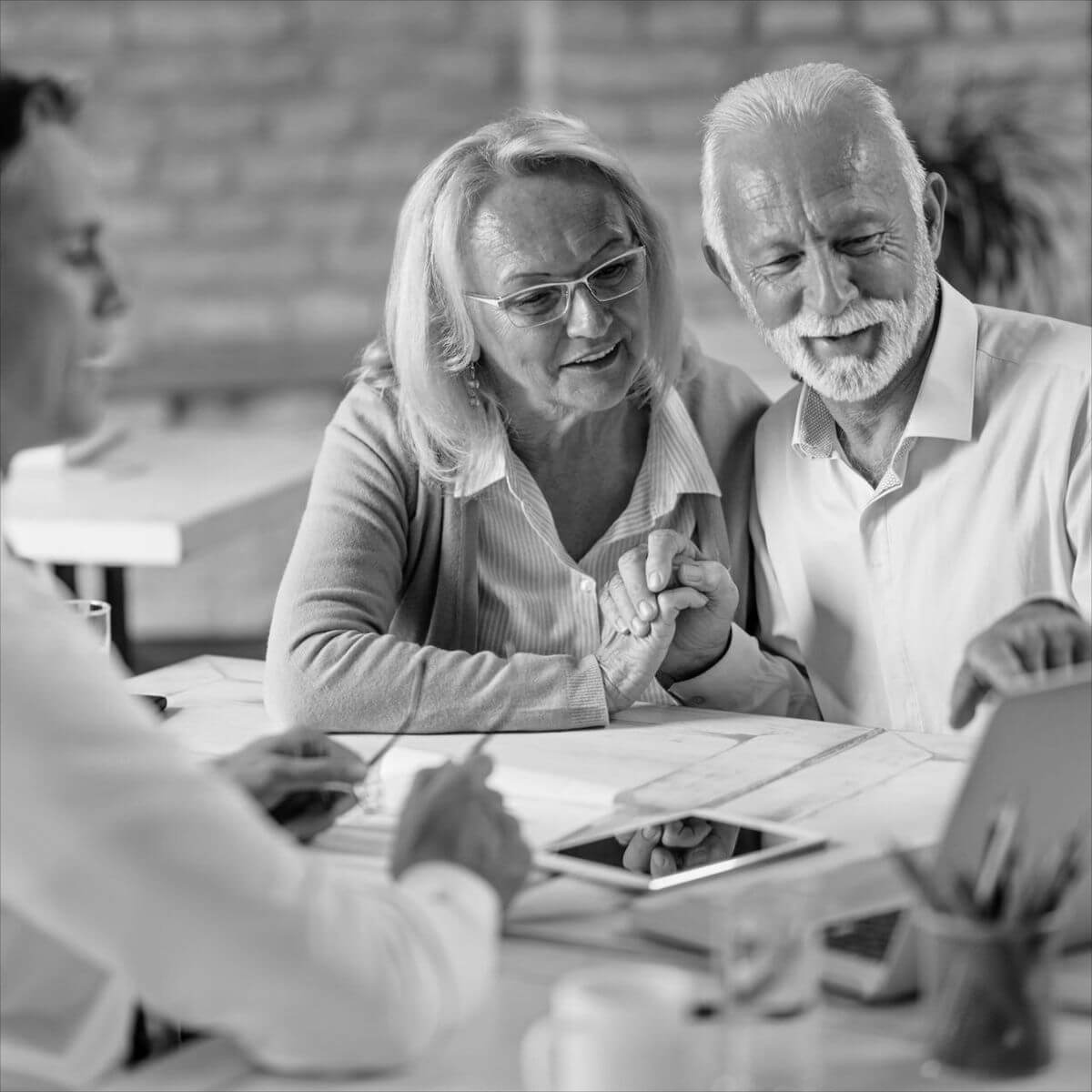 Idős házaspár tanácsadóval beszélget egy asztalnál, miközben végrendelet és öröklési szerződés részleteit egyeztetik, biztonságos öröklés tervezése céljából.