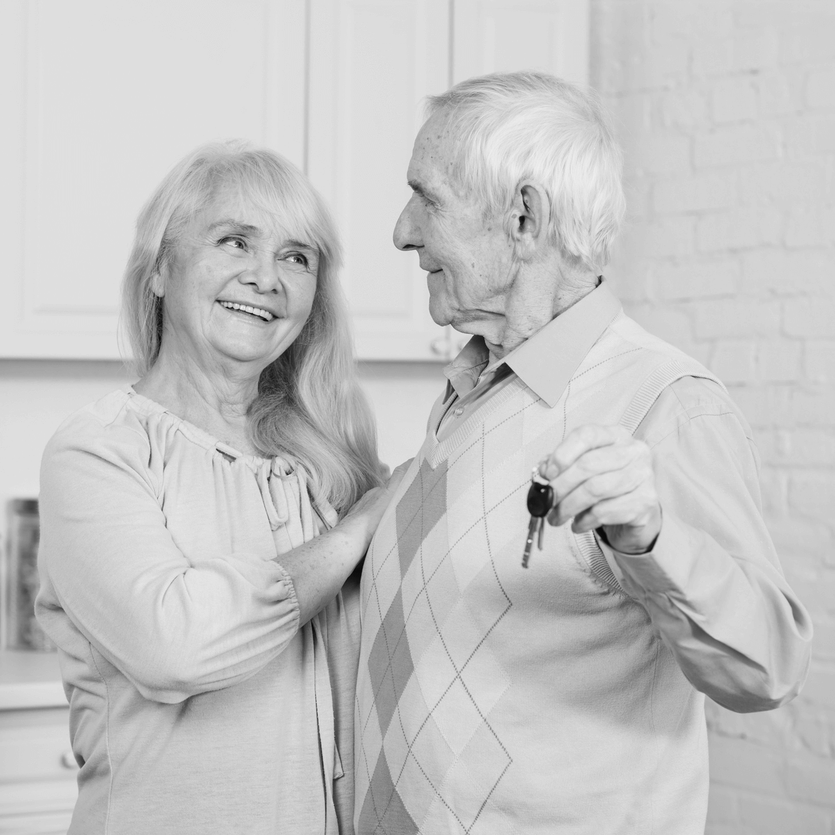 Idős házaspár boldogan mutatja az új otthonuk kulcsait, az ingatlan ajándékozás megható pillanata – családon belüli tulajdonátruházás érzelmi oldala.
