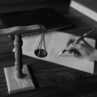 ingatlanjogi-szerzodes-alairas-merleggel Ügyvéd kézzel írja alá az ingatlan adásvételi szerződést, mellette egy jogi mérleg szimbólum – a kép az ingatlanjogi ügyvédi szolgáltatások részét képező szerződéskötést és jogi felelősséget ábrázolja.