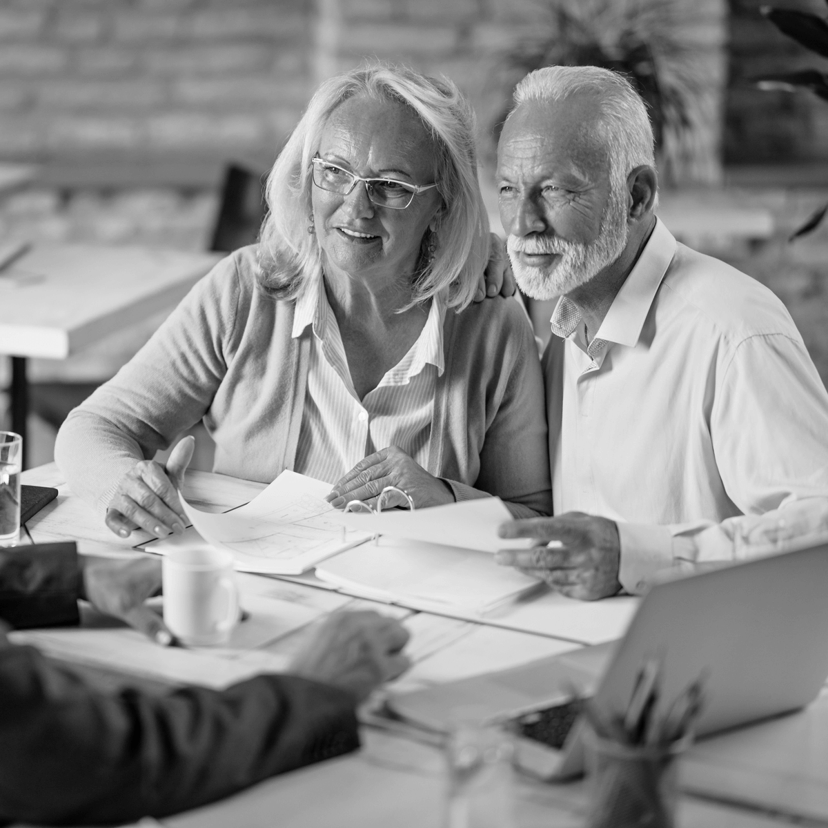 Idősebb házaspár ügyvédjükkel egyeztet a végrendelet és öröklési szerződés részleteiről, barátságos hangulatú jogi tanácsadás közben egy irodában.