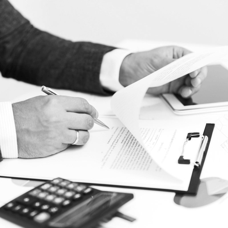 Ügyvéd végrendelet és öröklési szerződés szövegét ellenőrzi és aláírja egy irodában, iratok és számológép mellett, jogi dokumentumok előkészítése közben.